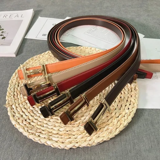Several thin leather belts in brown, red and cream coiled on a woven tray