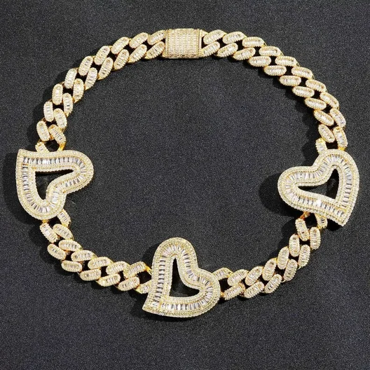 Gold-tone curb chain bracelet set with clear stones and three heart-shaped links, on a dark background