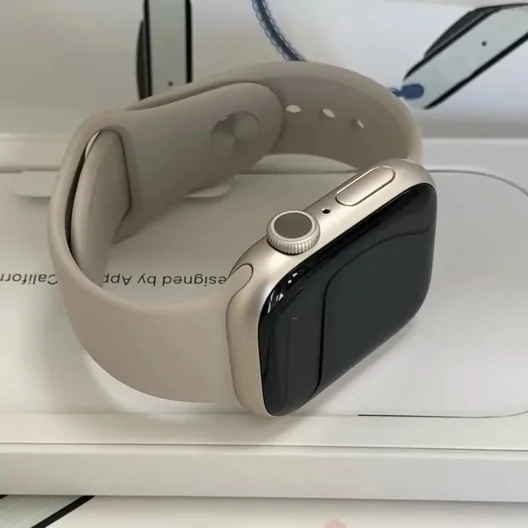 Smartwatch with a beige sport band resting on its white box
